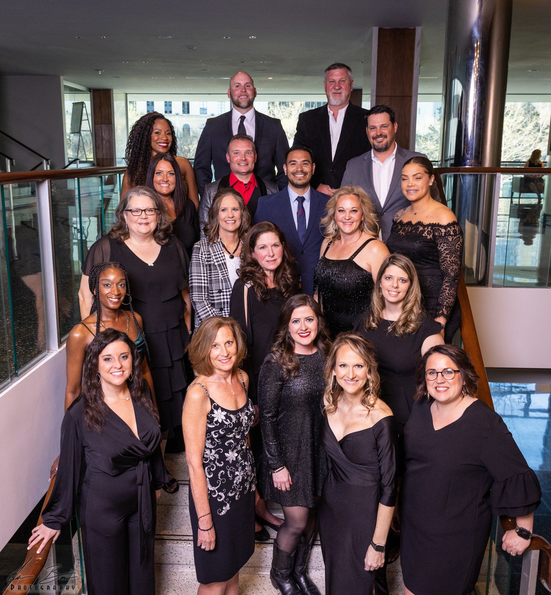 Group of diverse people in formal attire, posing on a staircase.