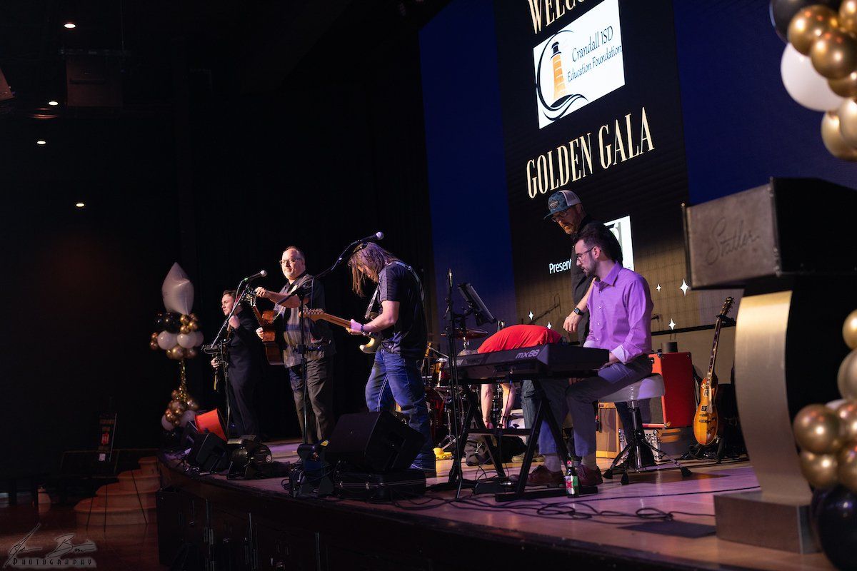 A band performs on stage at the Golden Gala. Musicians play instruments under stage lights.