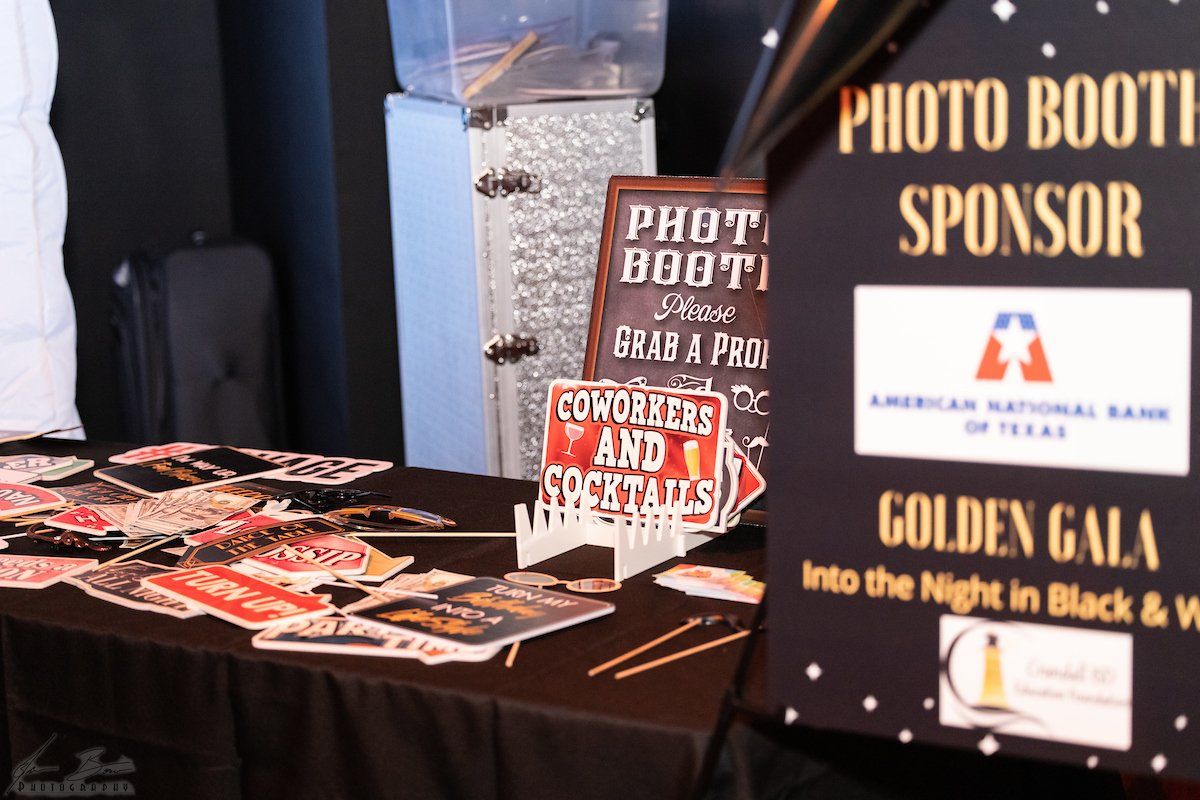 Photo booth at a gala sponsored by American National Bank of Texas, with props and a sign.