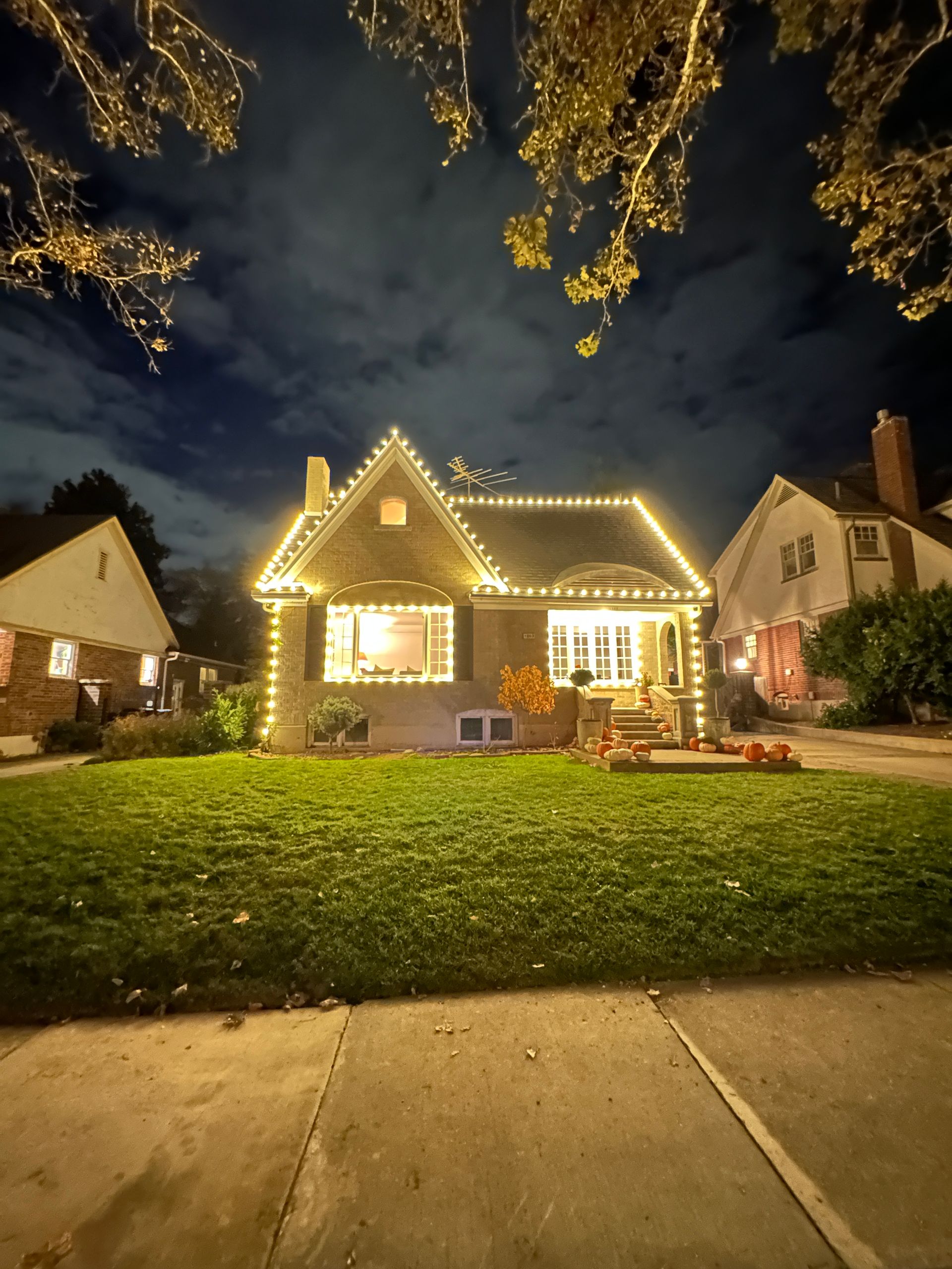 A house is decorated with christmas lights and pumpkins at night.