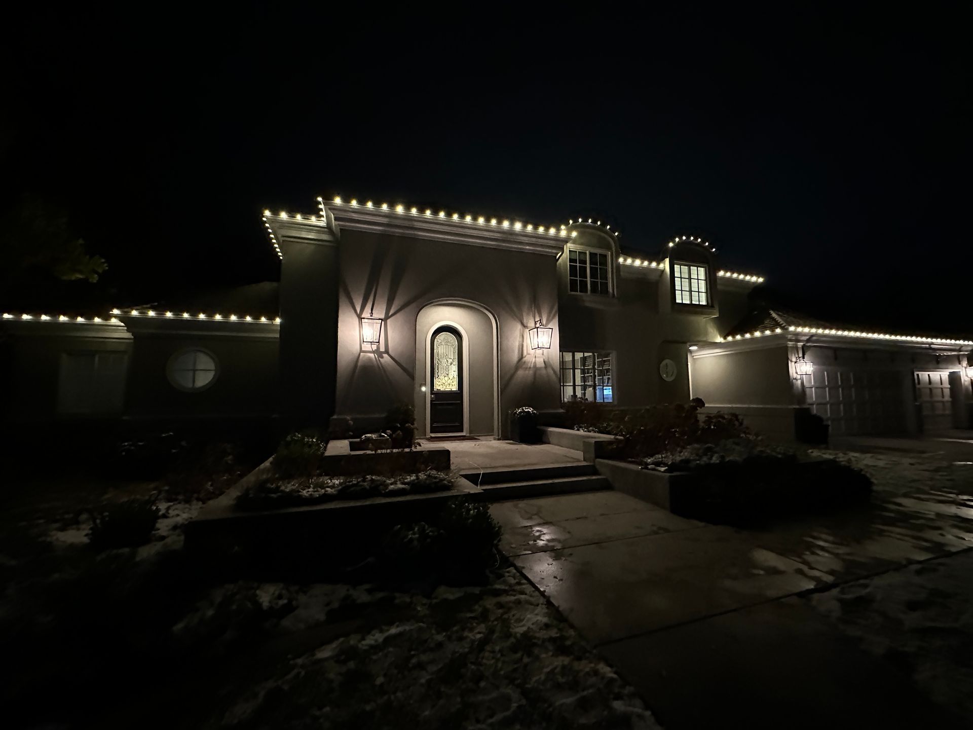 A house is decorated with christmas lights and trees at night.