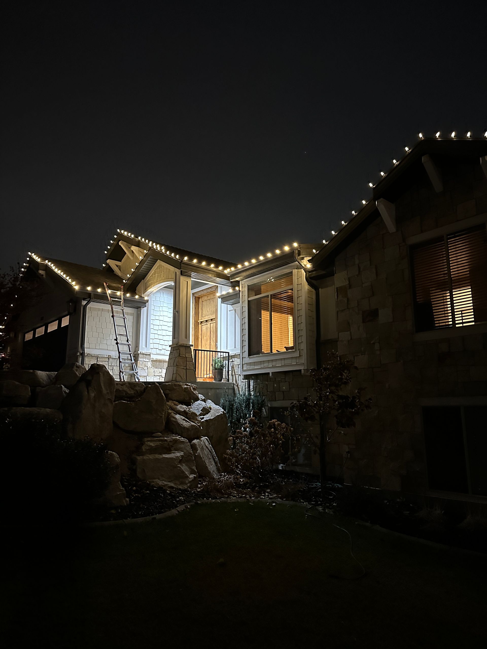 A house is decorated with christmas lights and pumpkins at night.