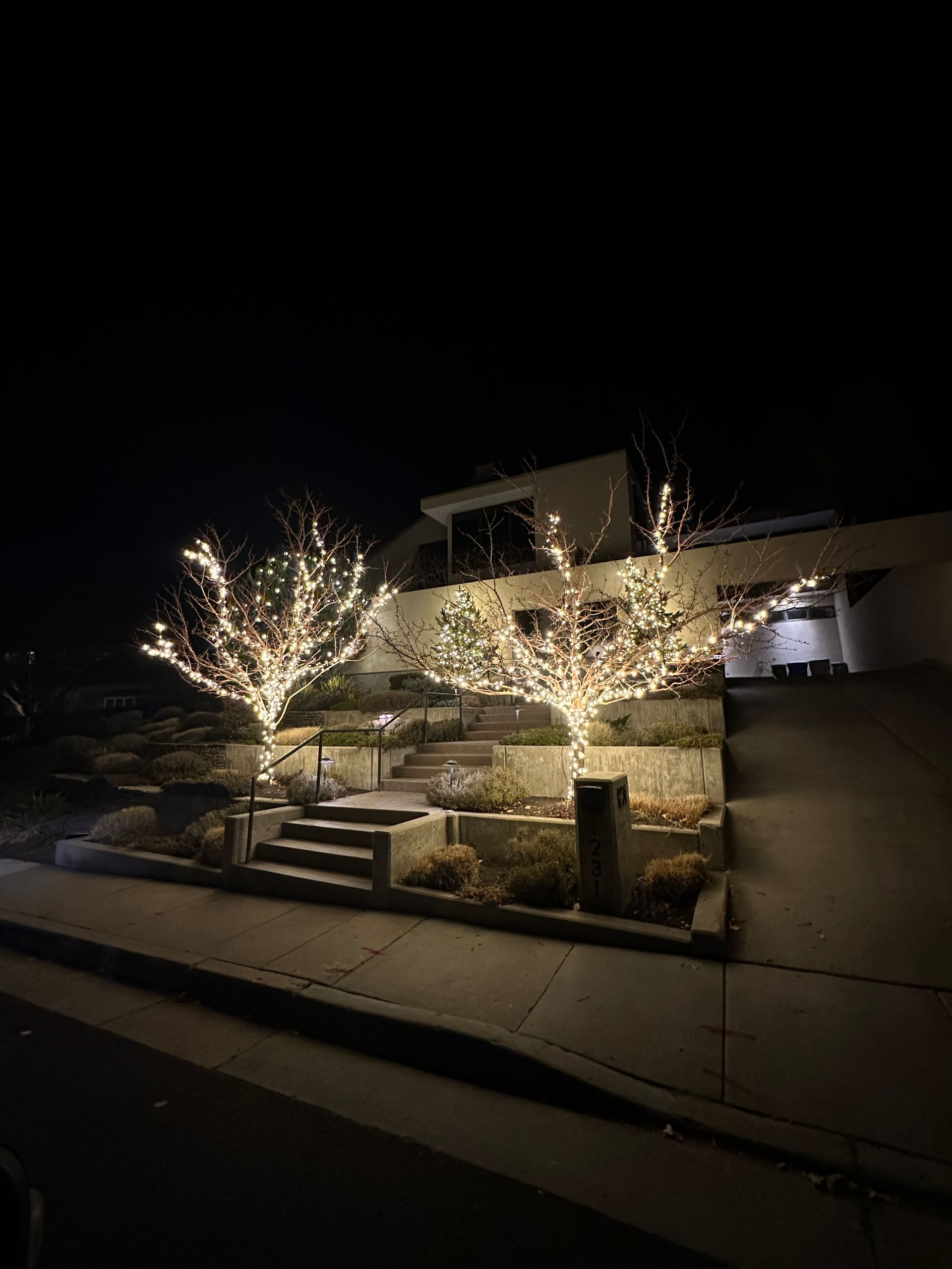 A house is decorated with christmas lights and pumpkins at night.