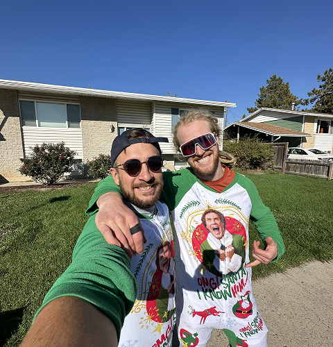 Two men are posing for a picture in front of a house.