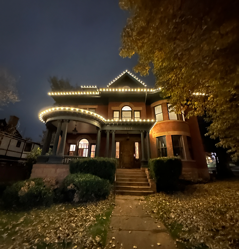 A large brick house is lit up at night with christmas lights.