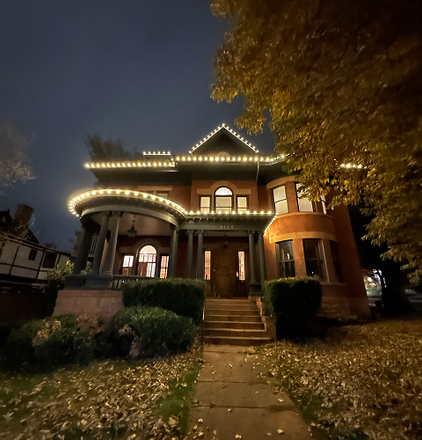 A large brick house is lit up at night with christmas lights.