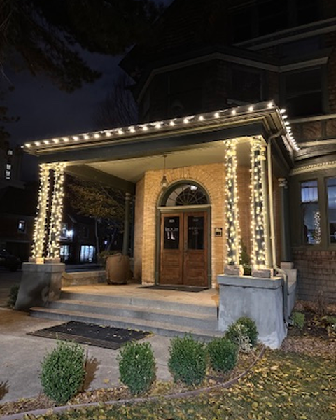A house is decorated with christmas lights and trees at night.