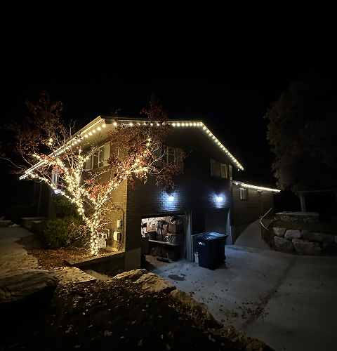 A house with christmas lights on it is lit up at night.