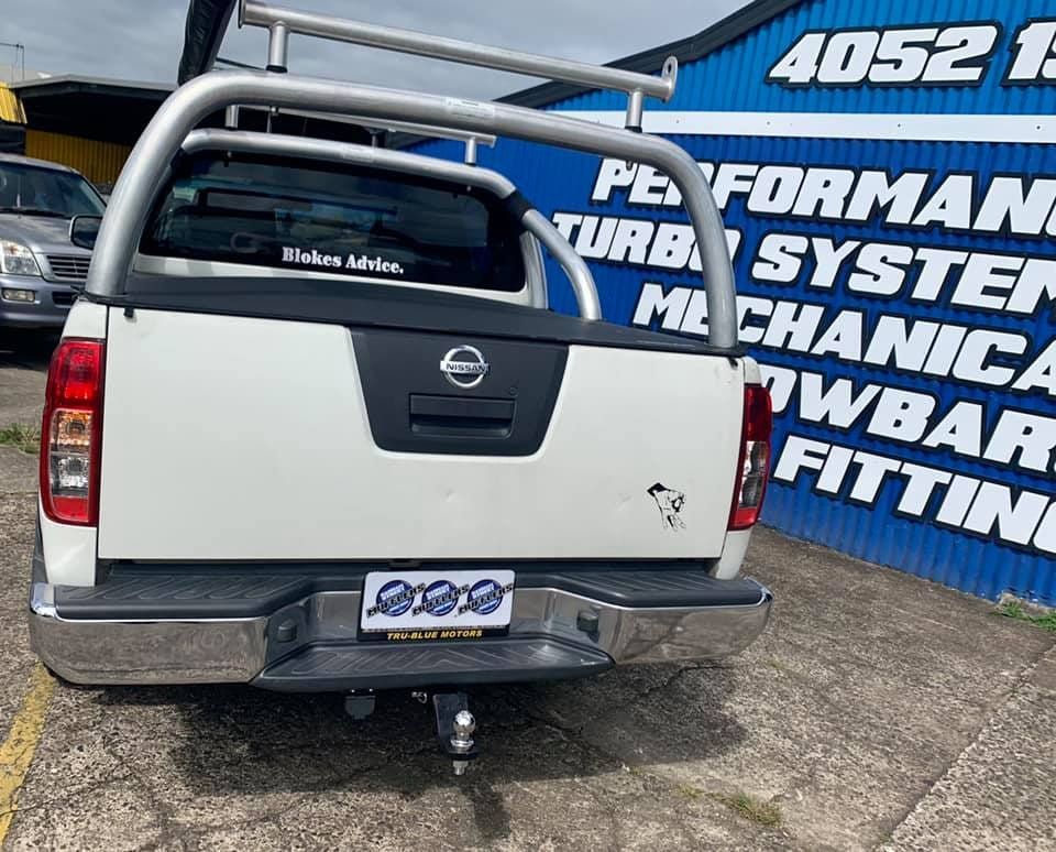 A White Nissan Pickup Truck Is Parked In Front Of A Blue Building — Hannam Street Mufflers and Mechanical In Bungalow, QLD