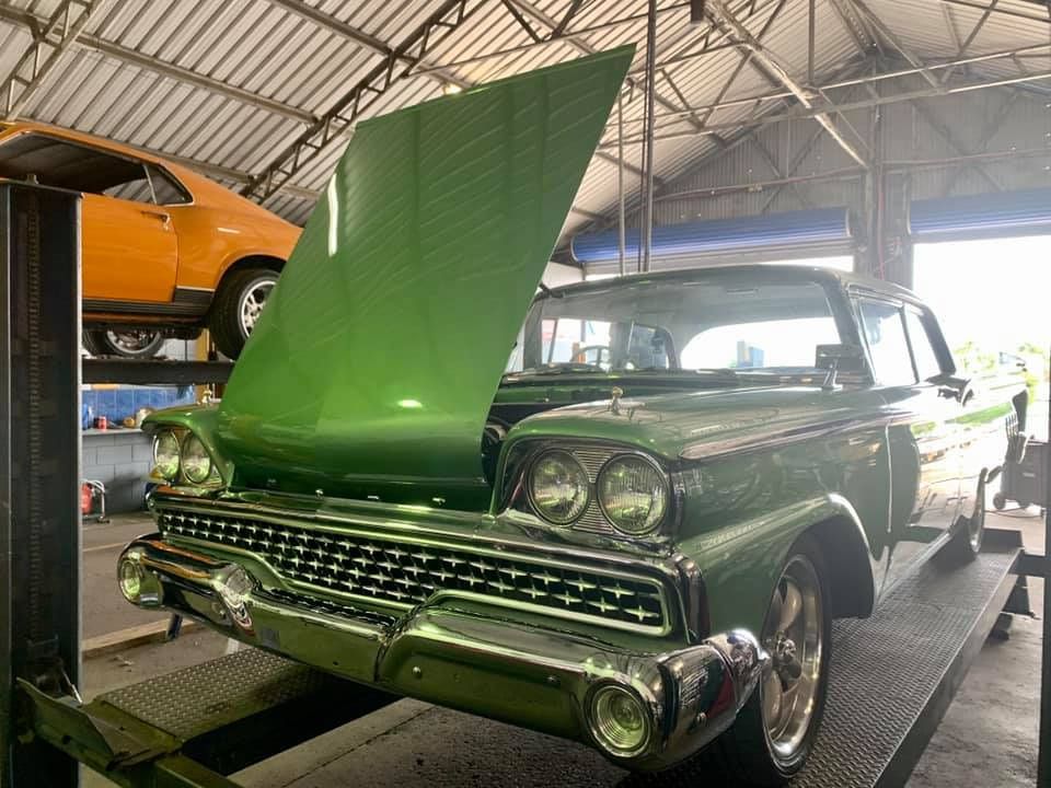 A Green Car With The Hood Up Is Parked In A Garage — Hannam Street Mufflers and Mechanical In Bungalow, QLD
