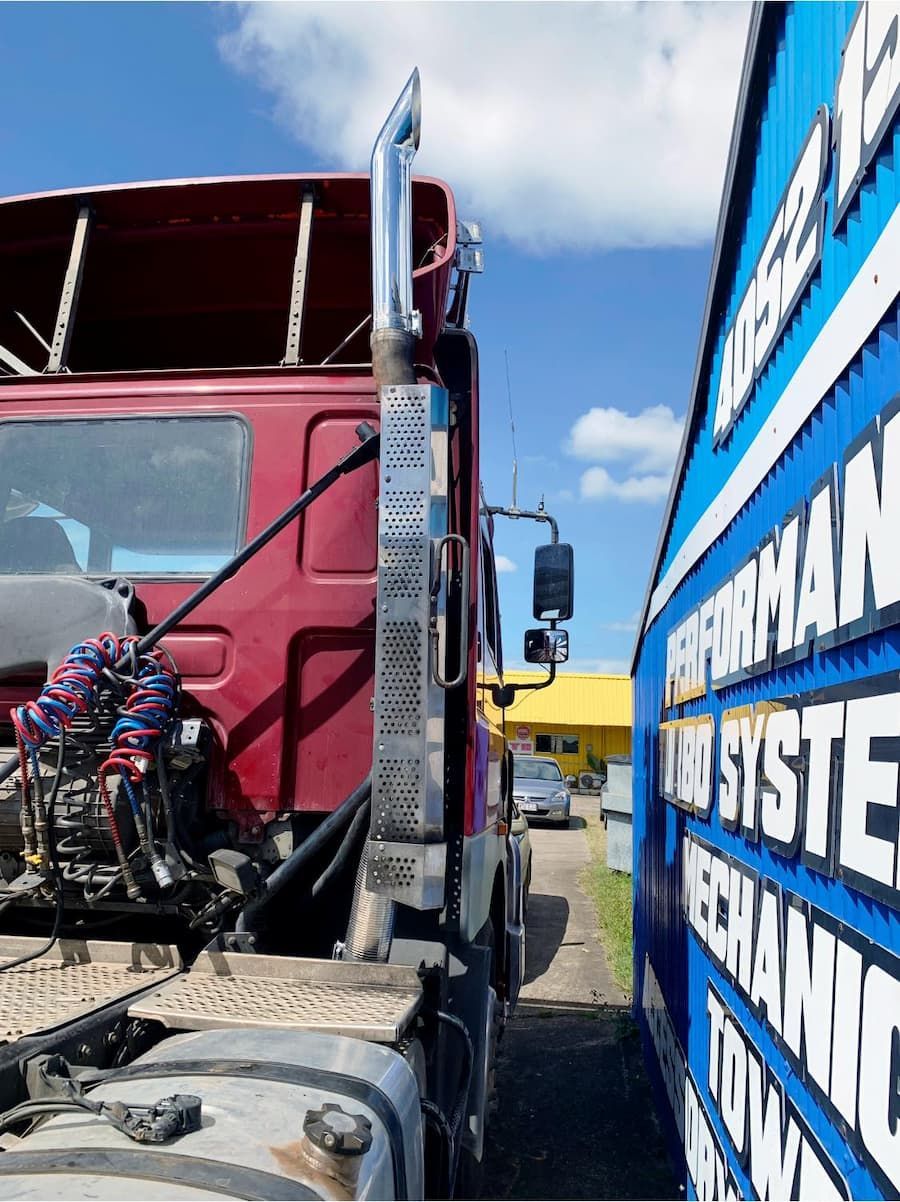 A Red Truck Is Parked Next To A Blue Truck That Says Mechanic — Hannam Street Mufflers and Mechanical In Bungalow, QLD