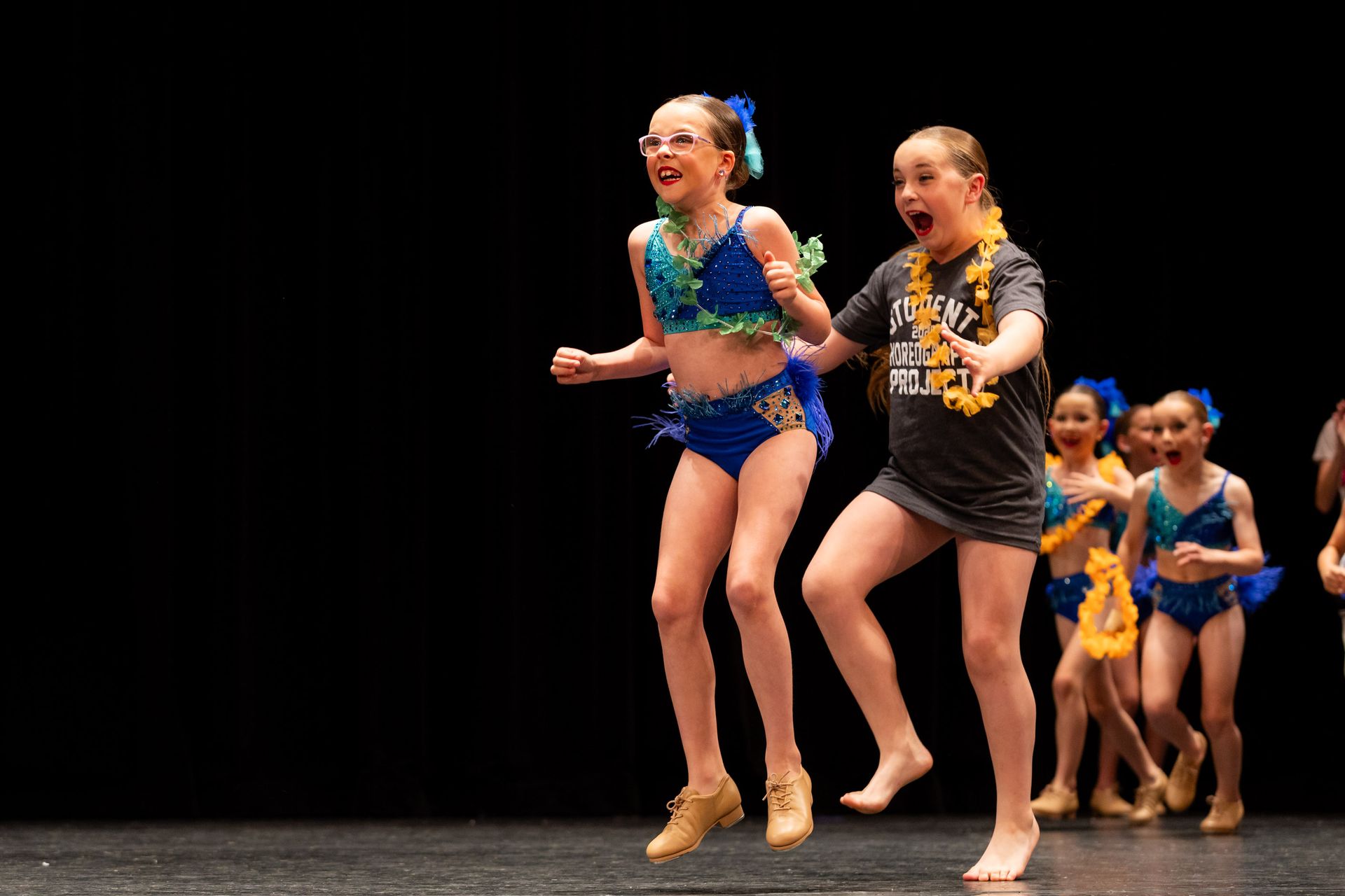 Children in dance costumes jumping on stage.