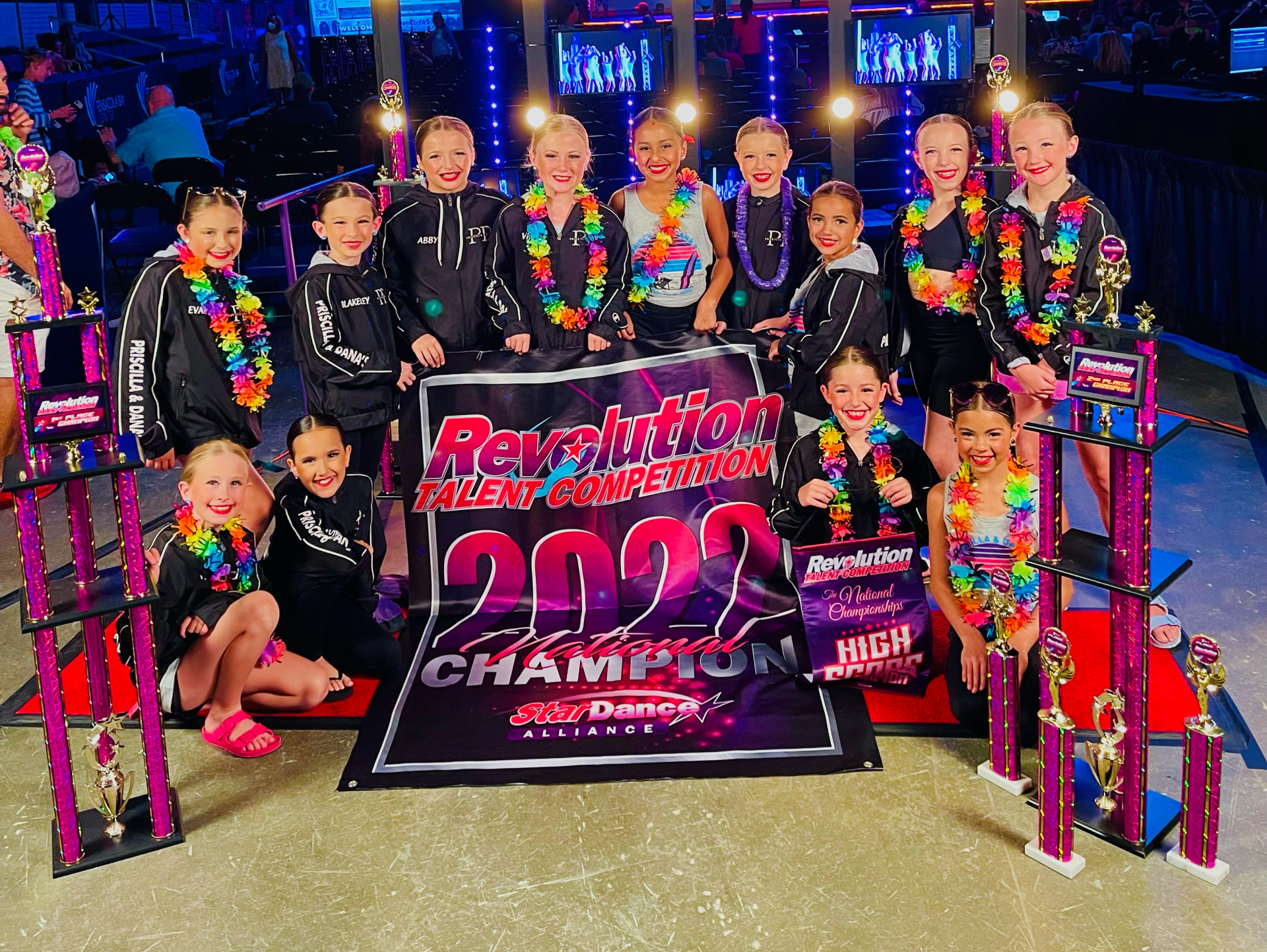 A group of young girls are posing for a photo in front of a sign that says revolution