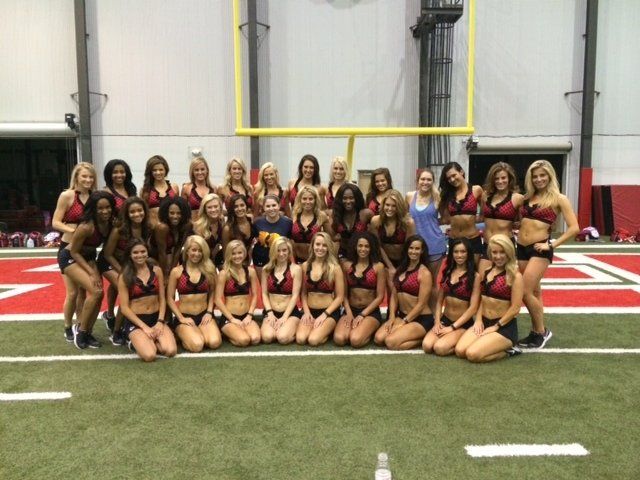 A group of cheerleaders are posing for a picture on a football field