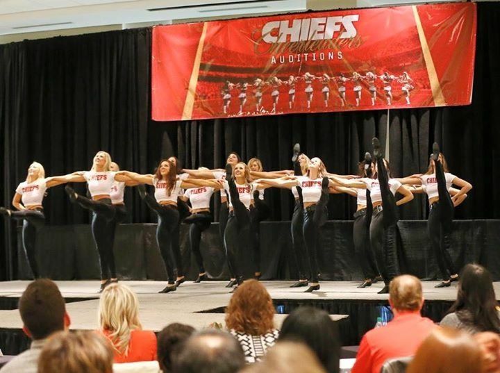 A group of women are performing on a stage in front of a chiefs banner