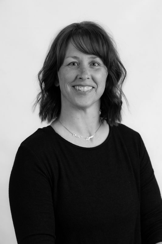 A woman in a black shirt is smiling in a black and white photo.