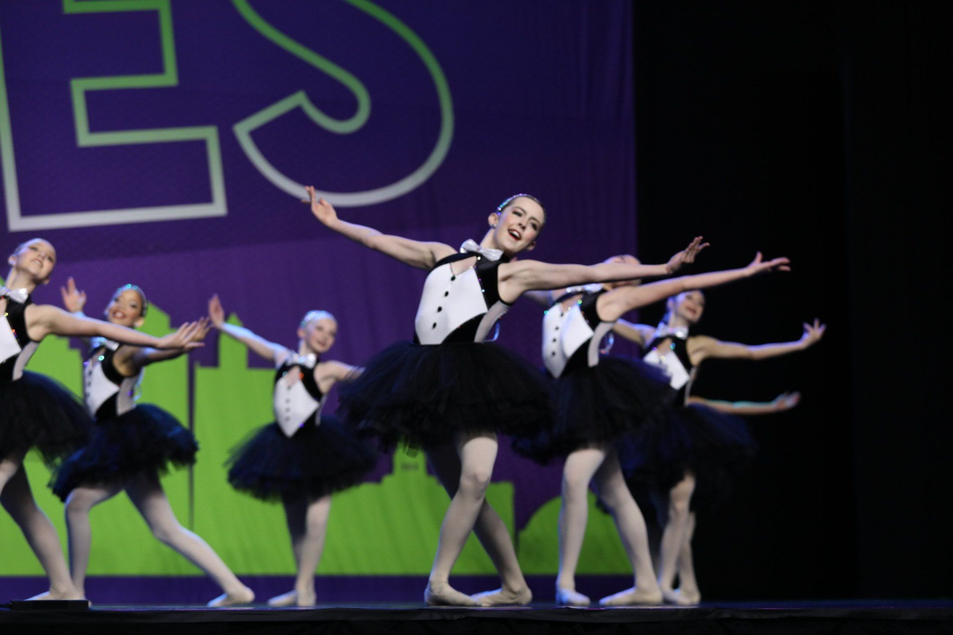 A group of young ballerinas are performing on a stage.