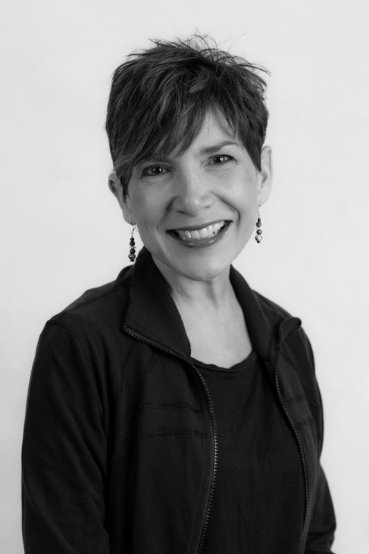 A woman in a black shirt is smiling in a black and white photo.