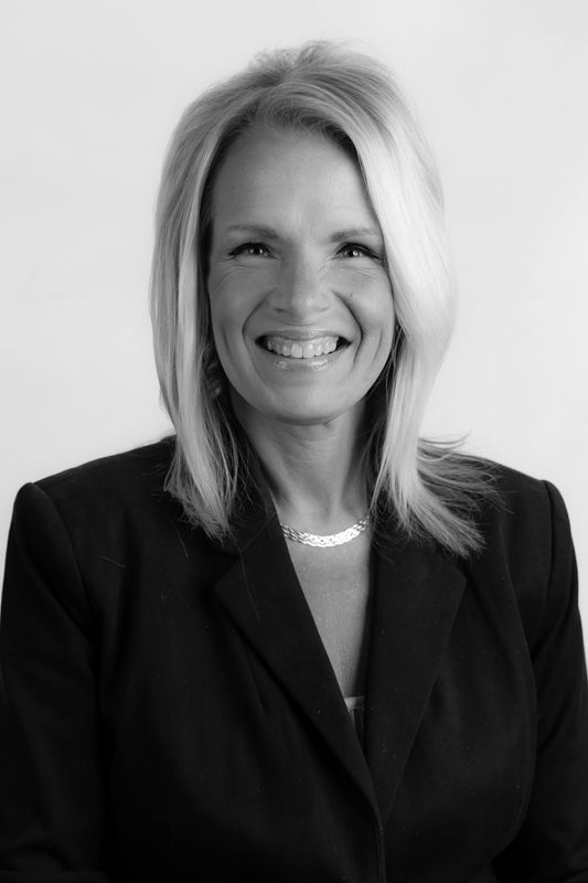 A woman with long blonde hair is smiling in a black and white photo.