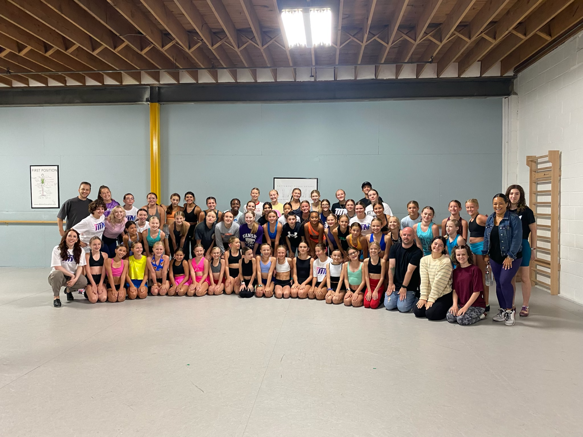 A large group of people are posing for a picture in a dance studio.