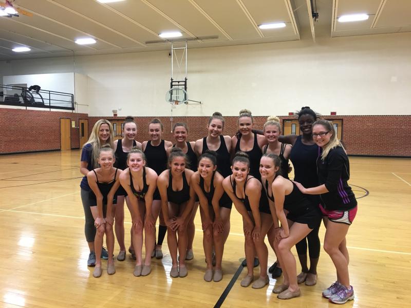 A group of young women are posing for a picture in a gym.