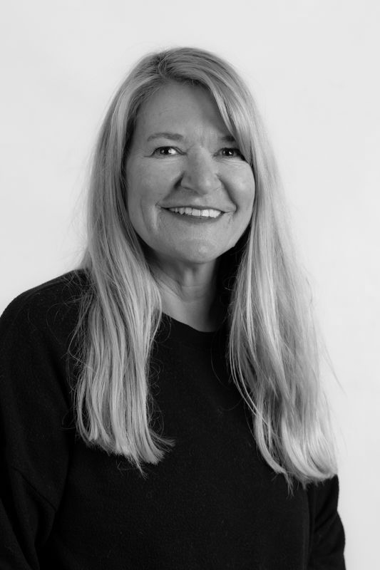 A woman with long hair is smiling in a black and white photo.