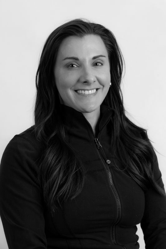 A woman with long hair is smiling in a black and white photo.
