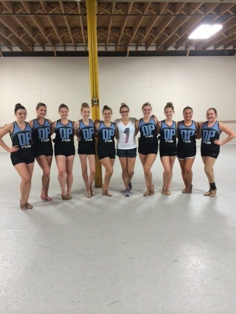 A group of girls are posing for a picture and one of them has the number 1 on her shirt