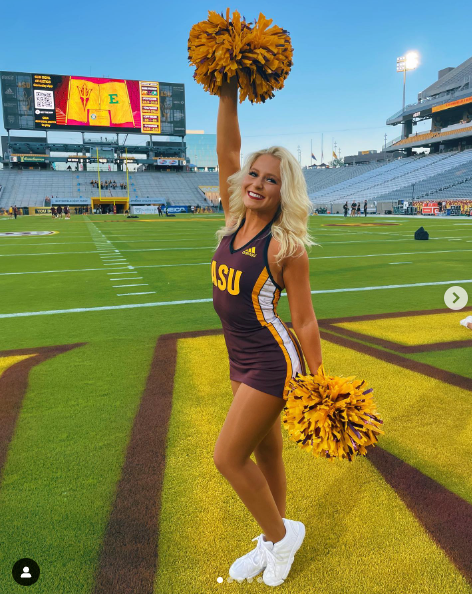 A cheerleader for lsu is holding a pom pom in the air