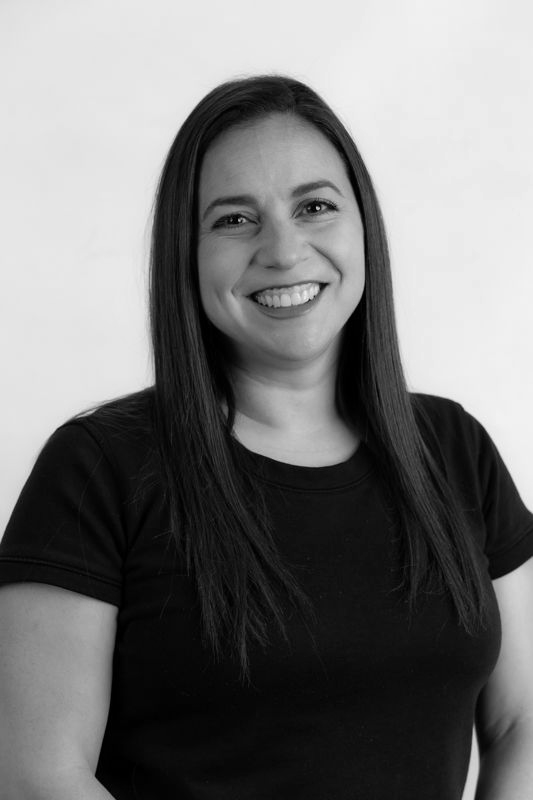 A woman with long hair is smiling in a black and white photo.