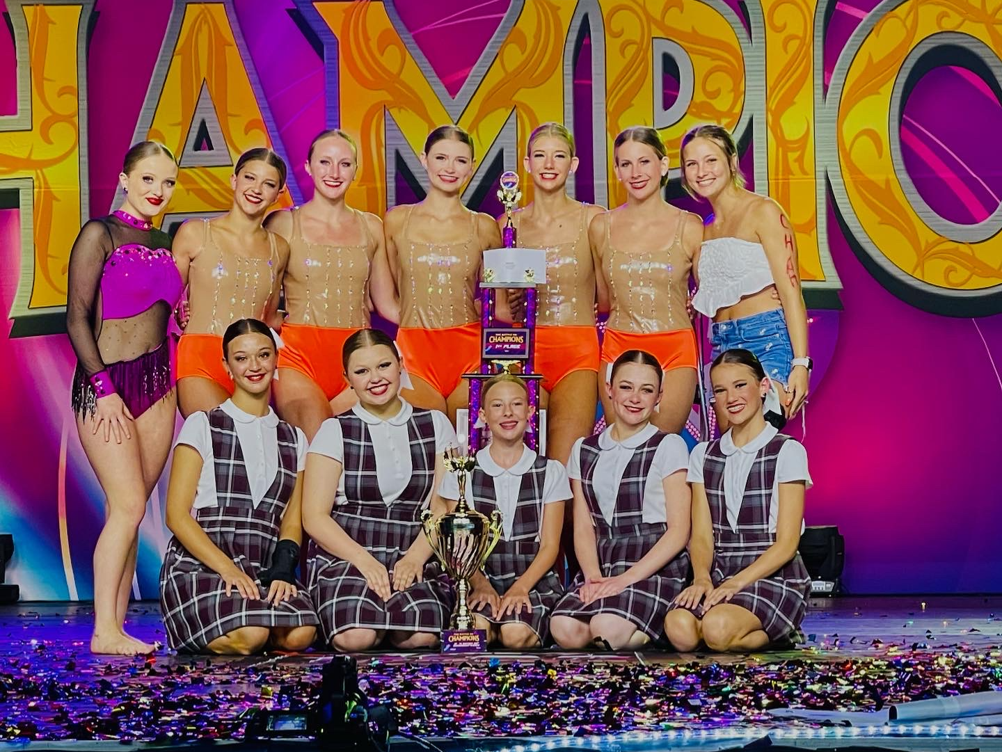 A group of young women are posing for a picture with a trophy.