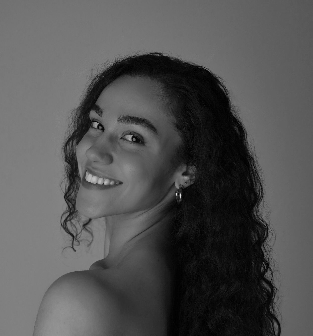 A woman in a black shirt is smiling in a black and white photo.