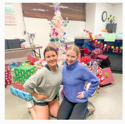 Two women are posing for a picture in front of a christmas tree.