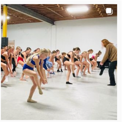 A group of young girls are standing in a line on a dance floor