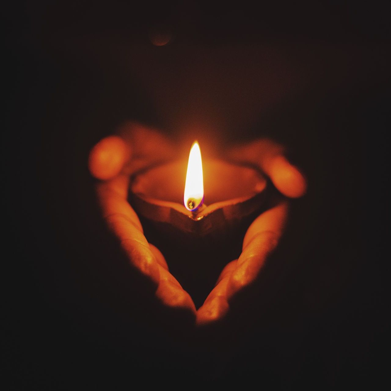 a person is holding a lit candle in their hands