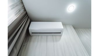 A white wall-mounted air conditioning unit installed above a window in a room.