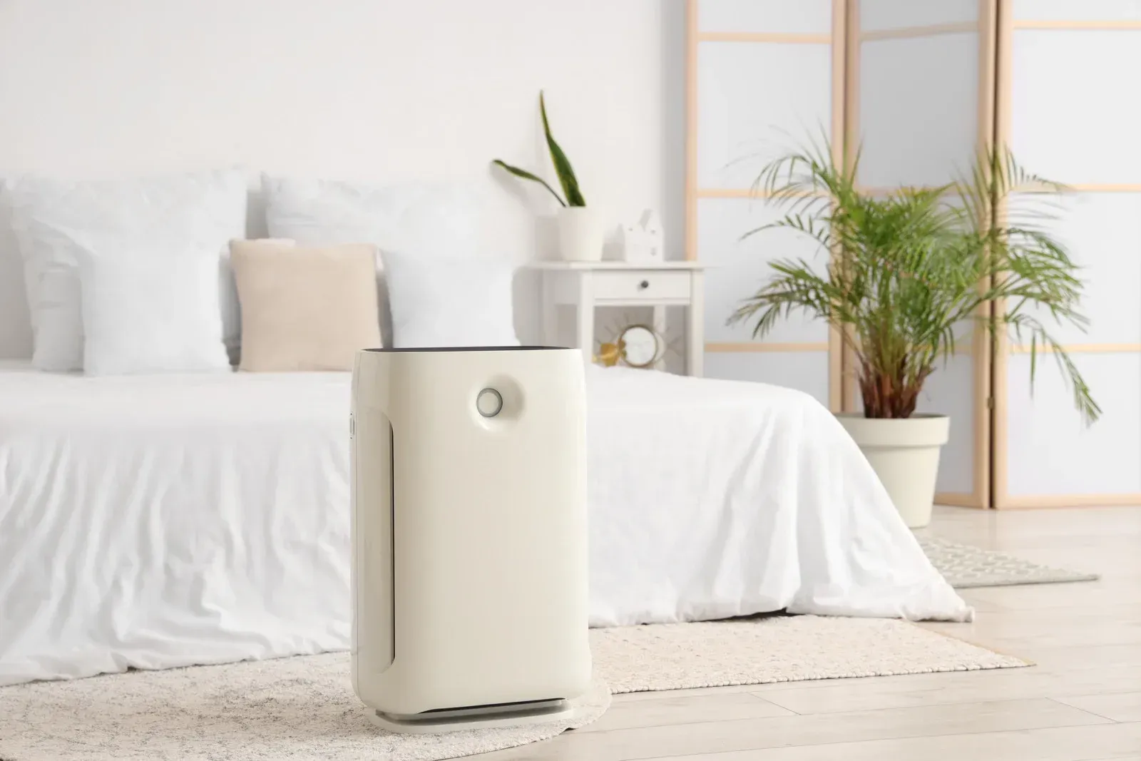 A white ceiling-mounted HVAC unit integrated into a drop ceiling, partially obscured by green indoor plant leaves.