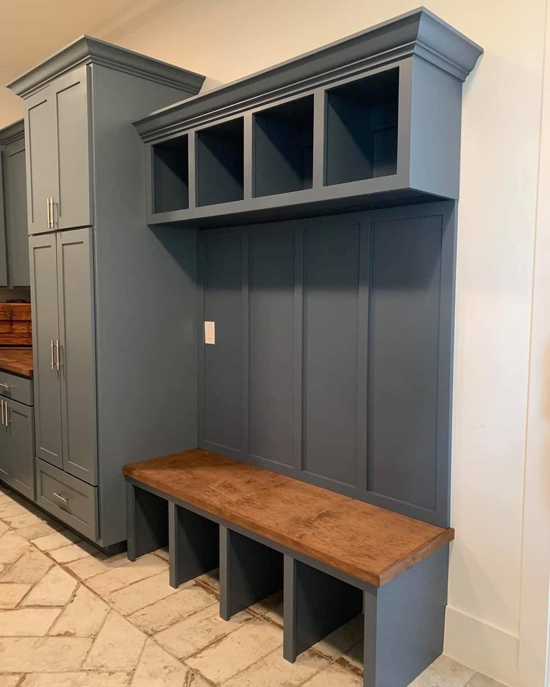 Blue built-in mudroom with cubbies, bench, and cabinetry on a patterned tile floor.