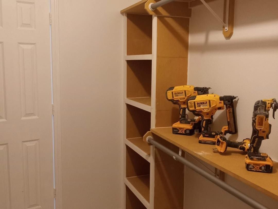 Closet interior with installed shelves and tools. Shelves are beige with white walls and door. Tools sit on a shelf.