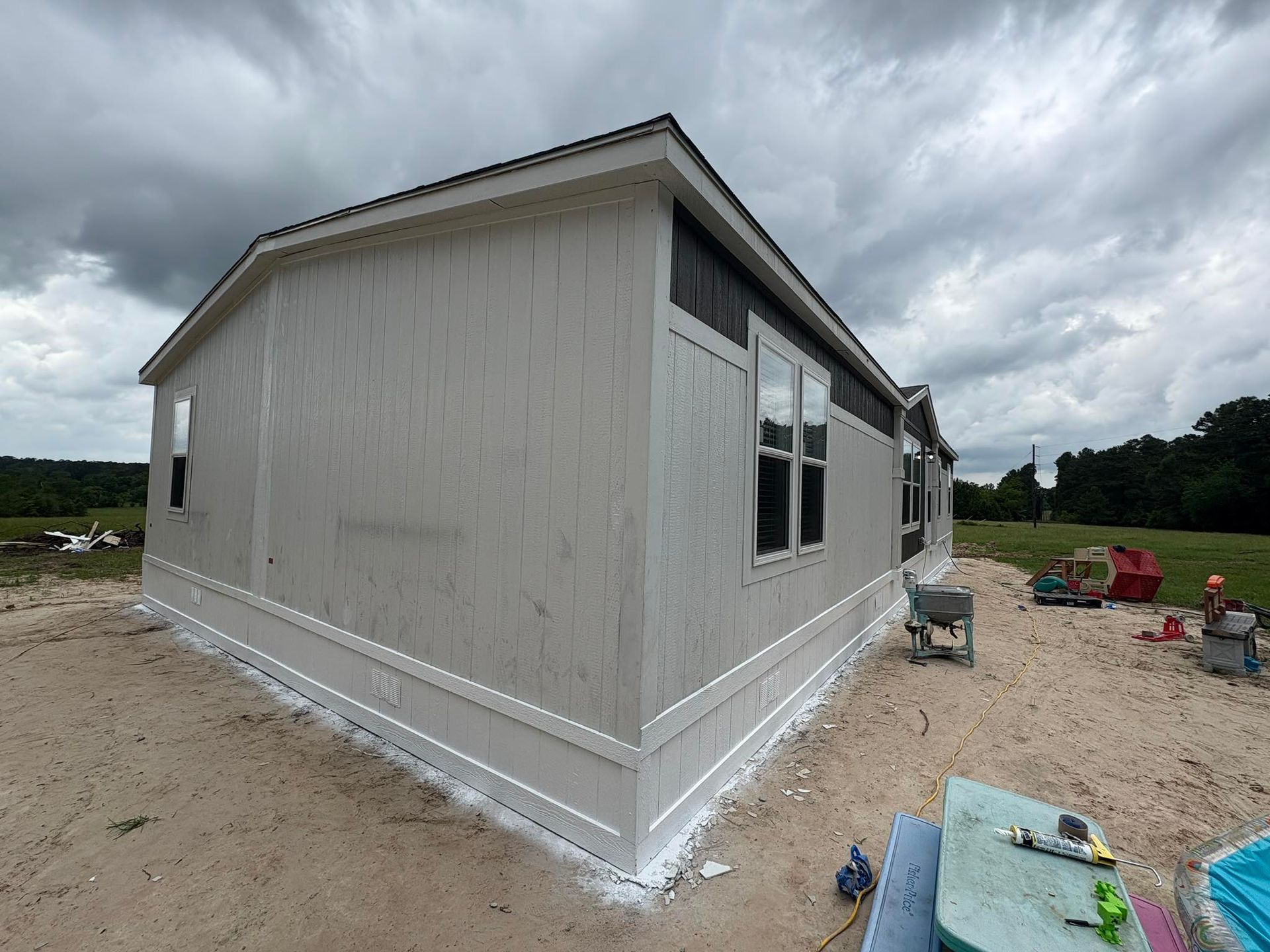 Side view of a light gray house under construction on a cloudy day.
