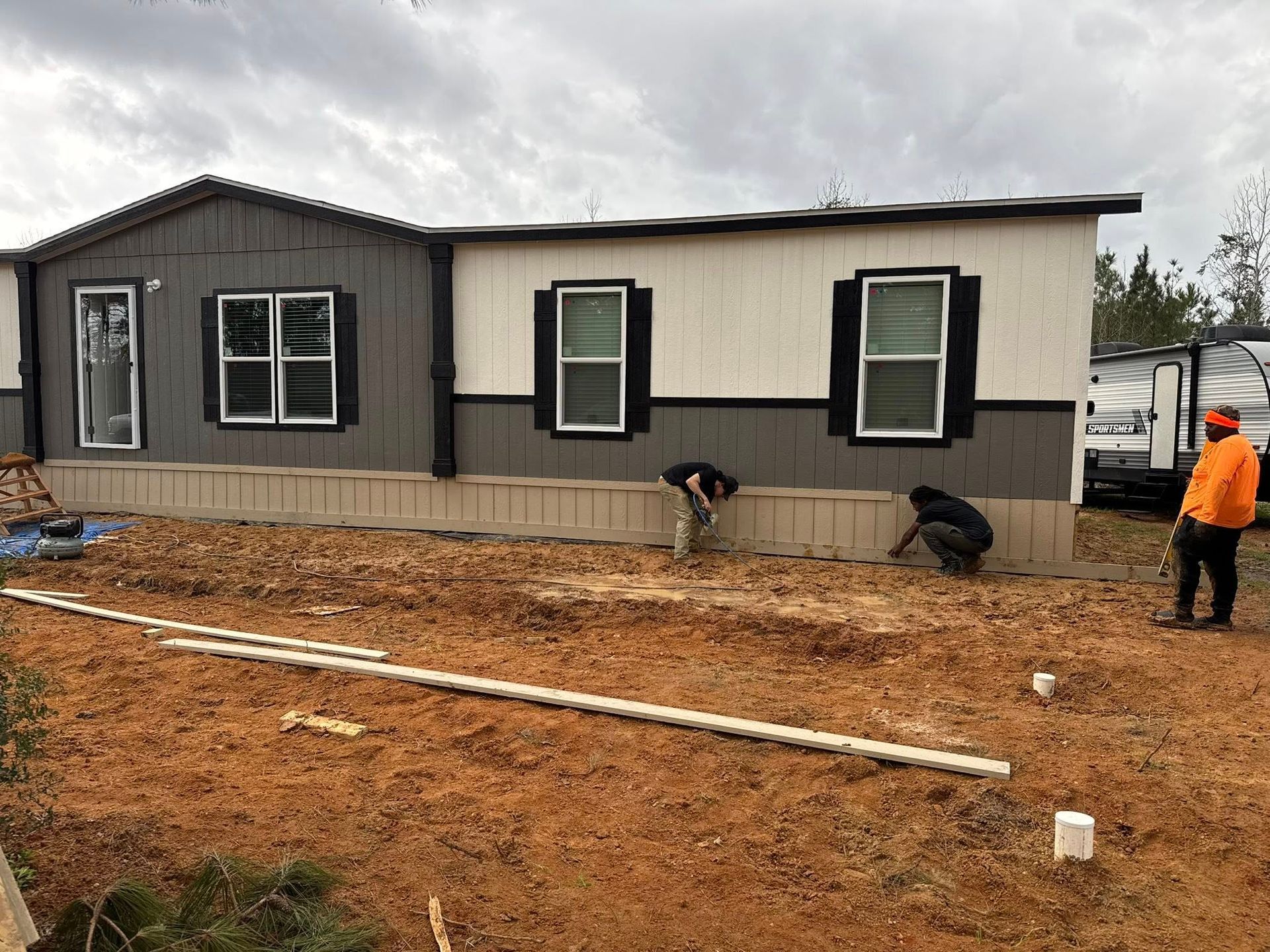 Workers install siding on a house exterior.  The team is comprised of four people, with varying skin tones.