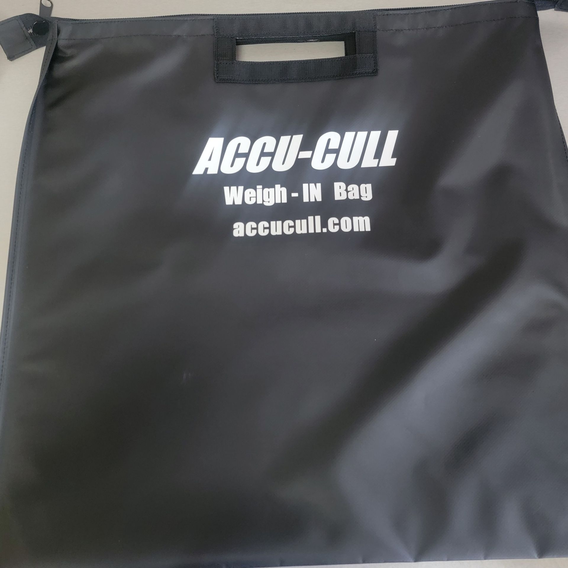 A person is holding a black bag that says accu-cull on it