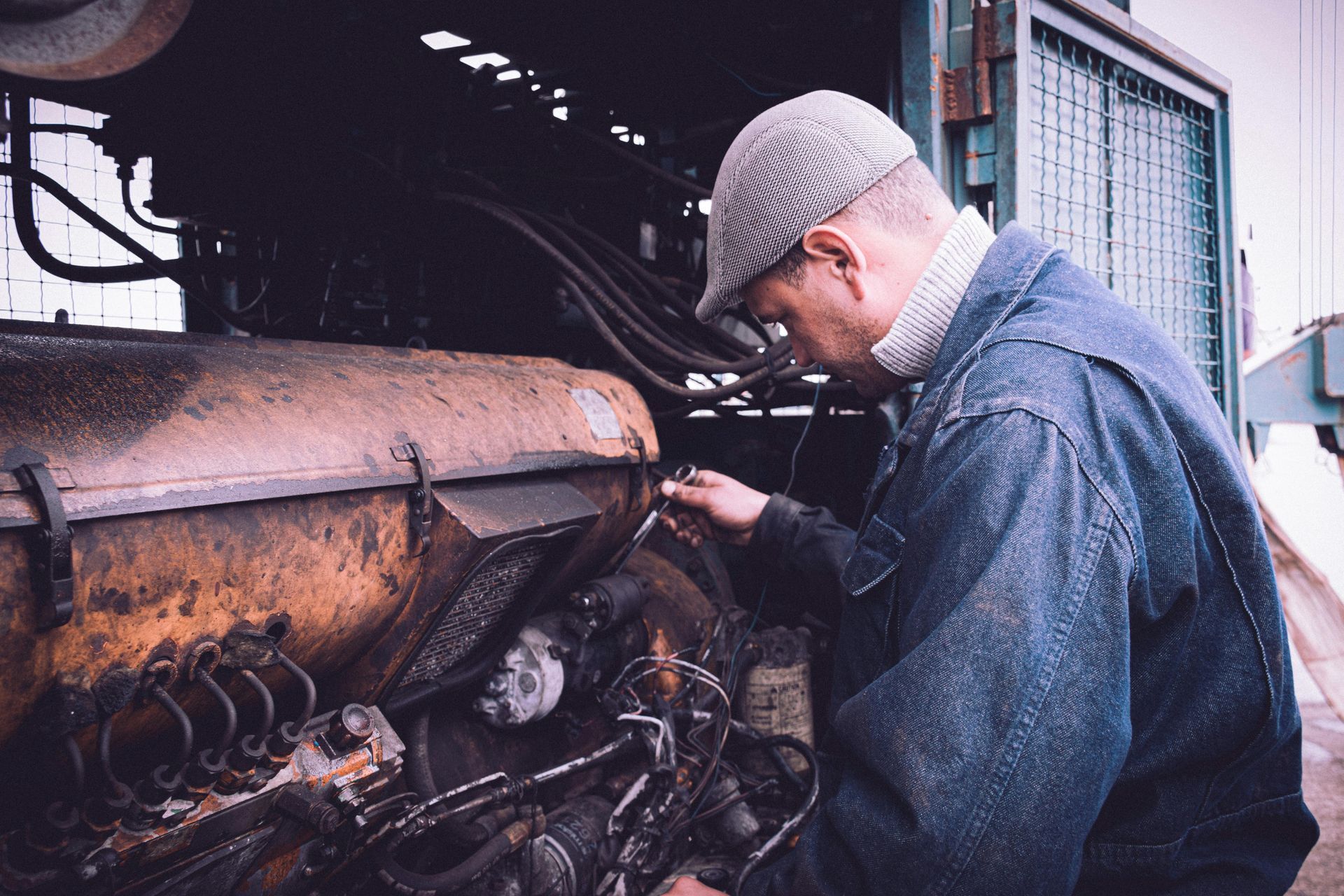 Mechanic inspects undercarriage of a car with a wrench and flashlight.