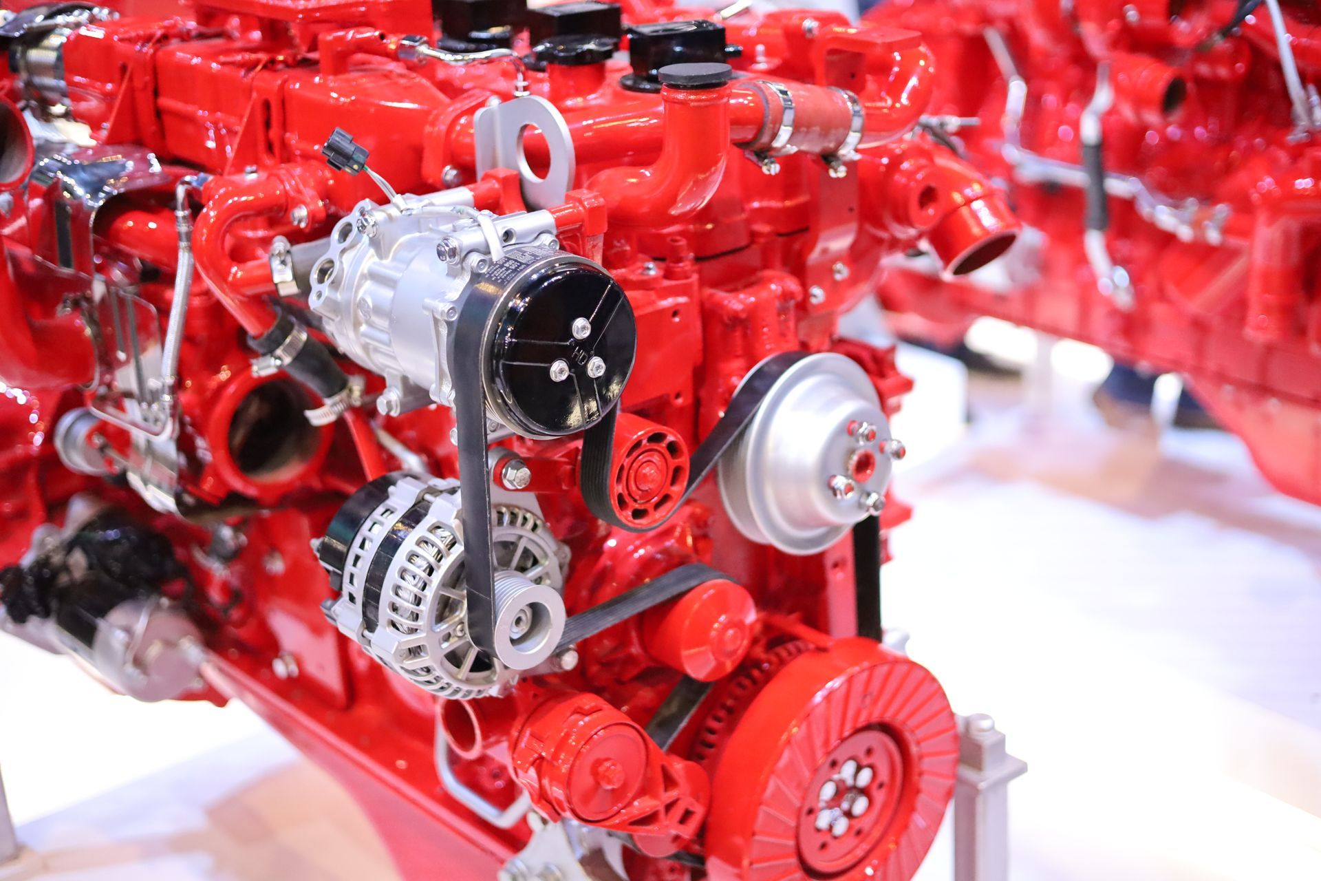 Car engine with hood open, black car, showing engine components, outdoor setting.