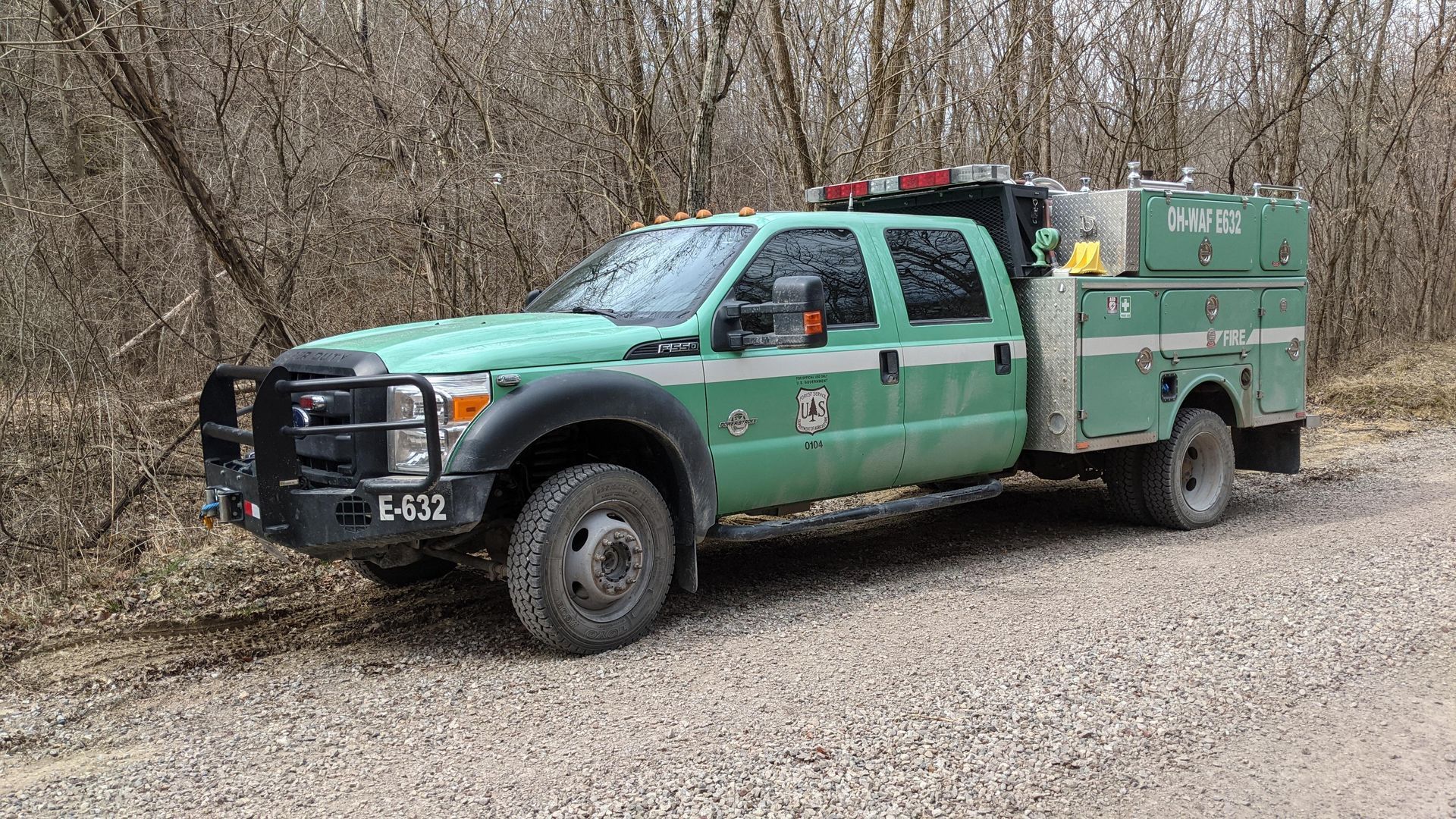 Mechanic working under a black car lifted on a hoist in a garage.