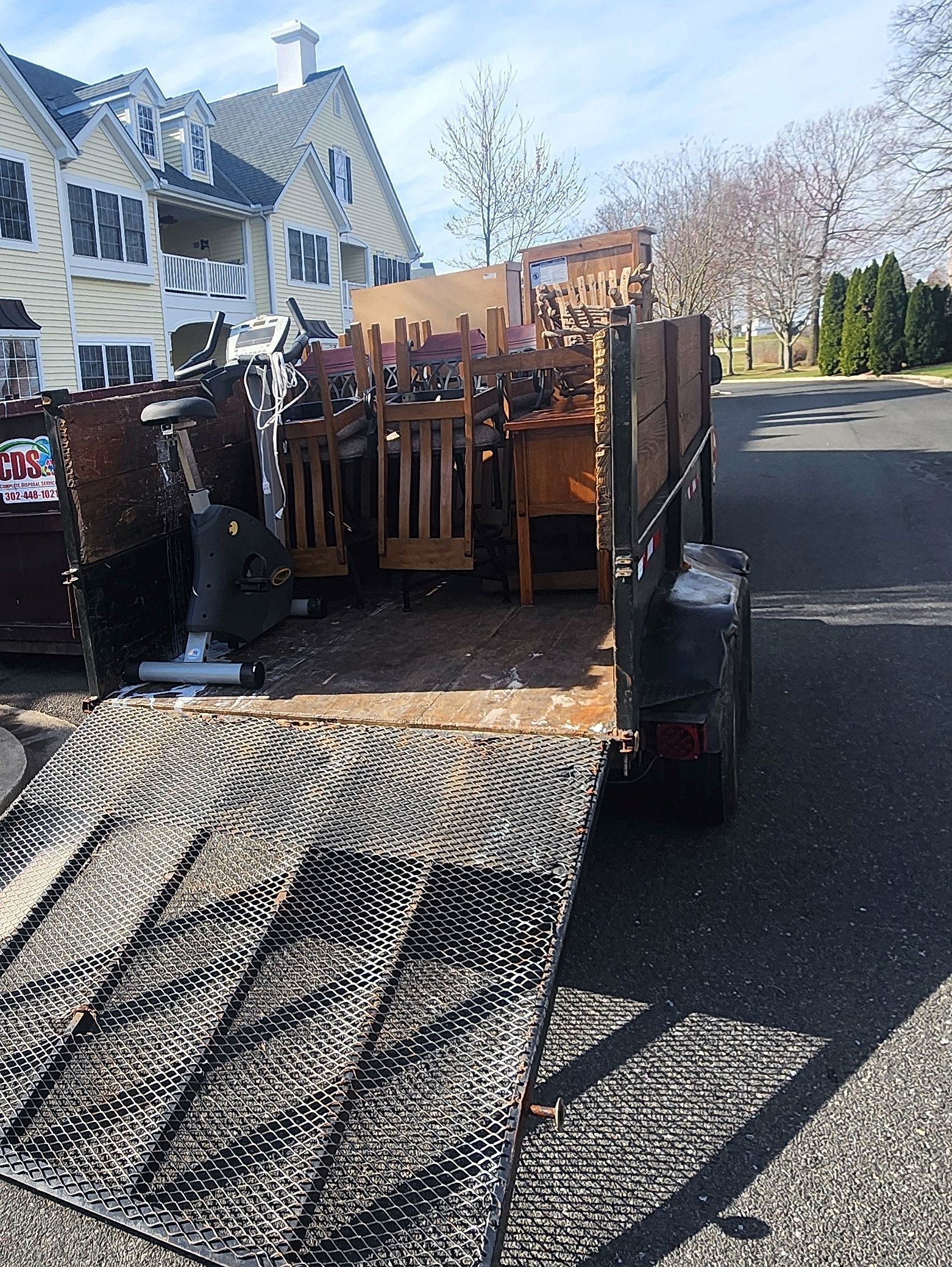 A trailer filled with furniture is parked in front of a house.