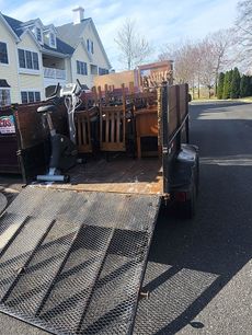 A trailer filled with furniture is parked in front of a house.