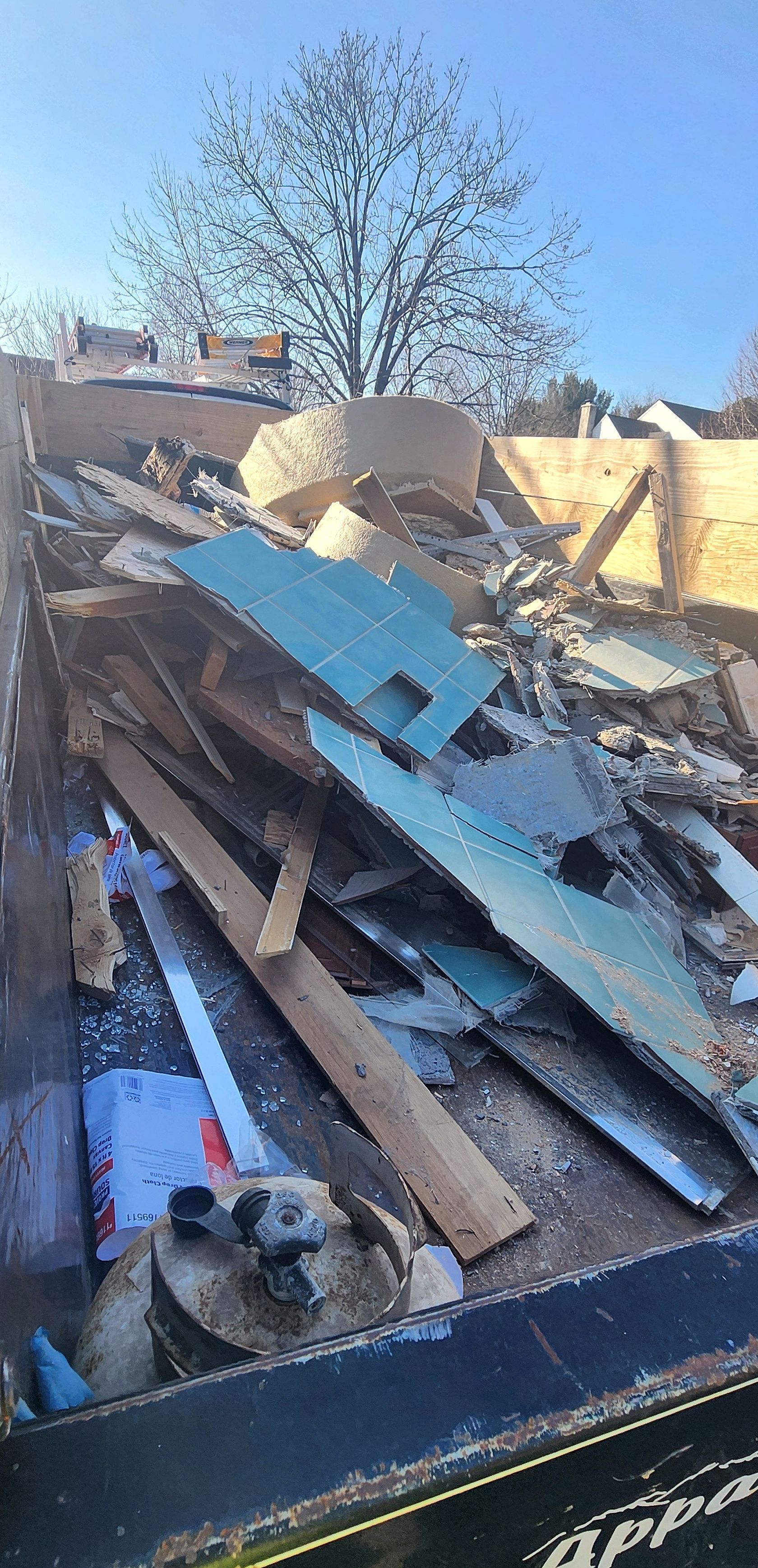 A pile of wood and metal is sitting in a dumpster.