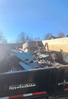 A dumpster filled with a lot of trash on a sunny day.