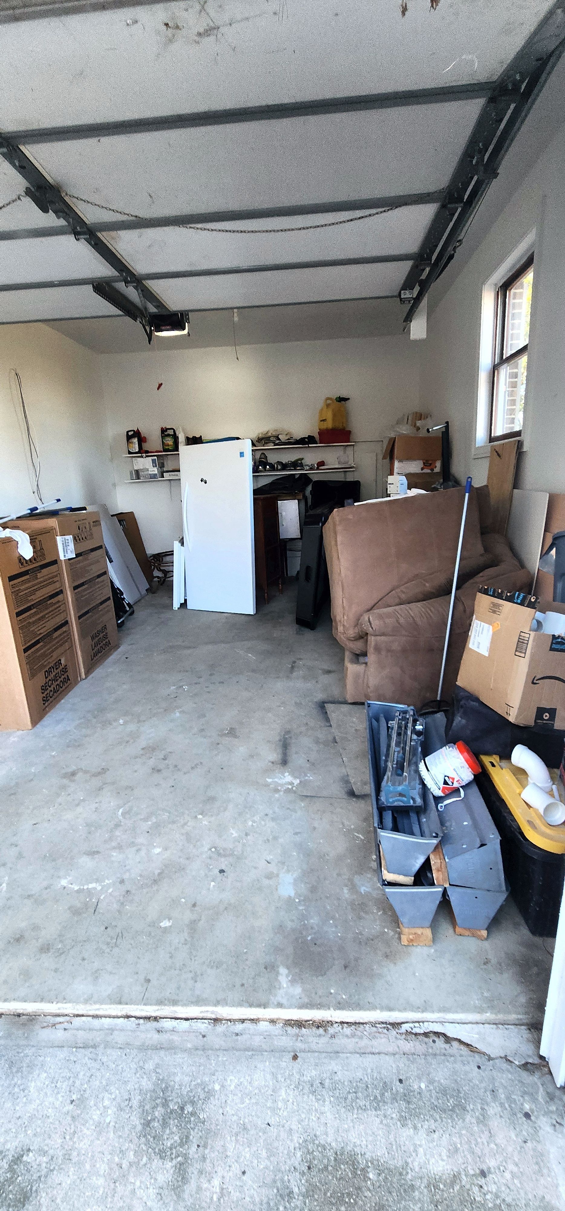 A garage filled with lots of boxes and a refrigerator.